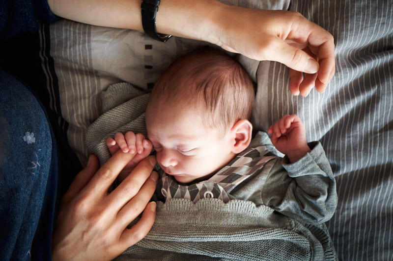 mama halt babys hand bei neugeborenenshooting